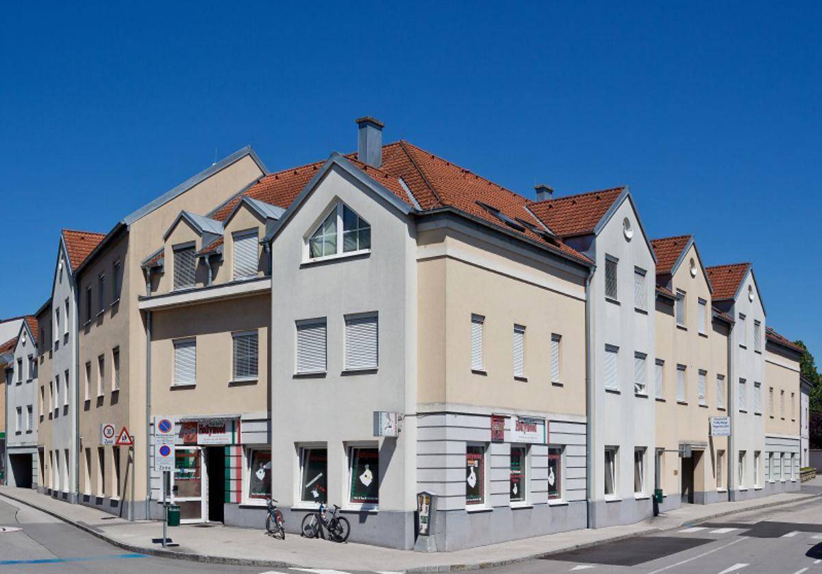 Gebäudeansicht von der Straßenseite mit Geschäften im Erdgeschoss und Fahrrädern davor.
