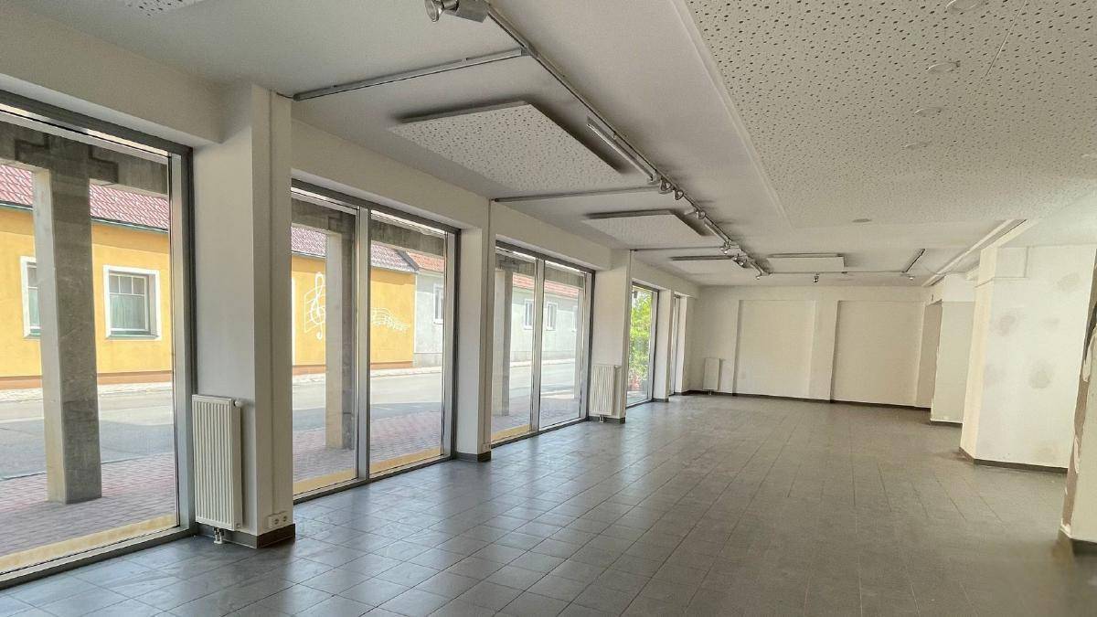 Geräumige, leere Geschäftsfläche im Erdgeschoss mit großen Schaufenstern zur Straße hin.