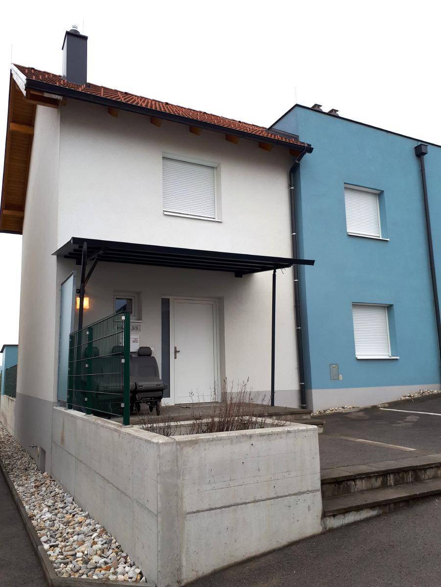 Vorderansicht zweier Reihenhäuser mit weißer und blauer Fassade sowie Rollläden an den Fenstern.