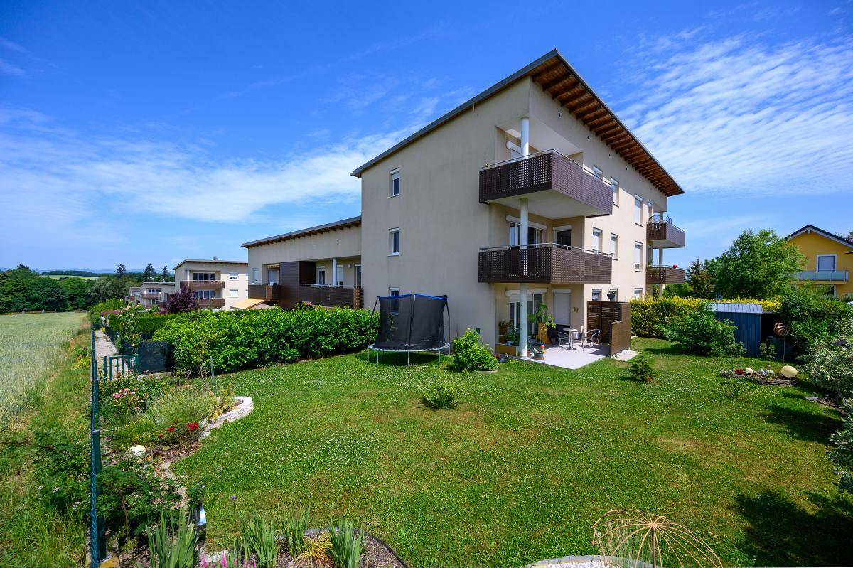 Gartenbereich hinter dem Gebäude mit Rasenfläche, Trampolin und Zugang zu den Terrassen.