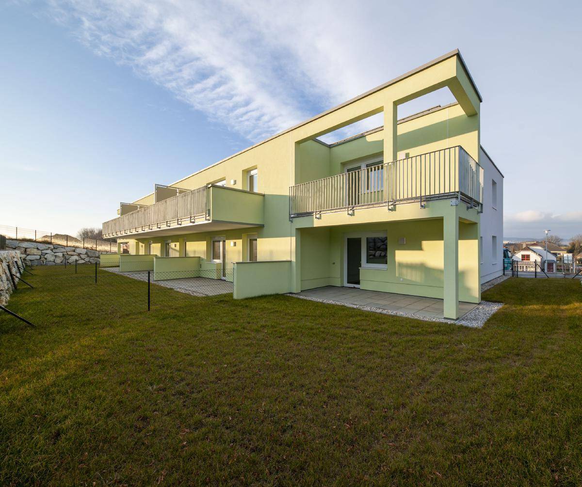 Ansicht des modernen Gebäudes mit privaten Terrassen und Rasenflächen im Erdgeschoss.