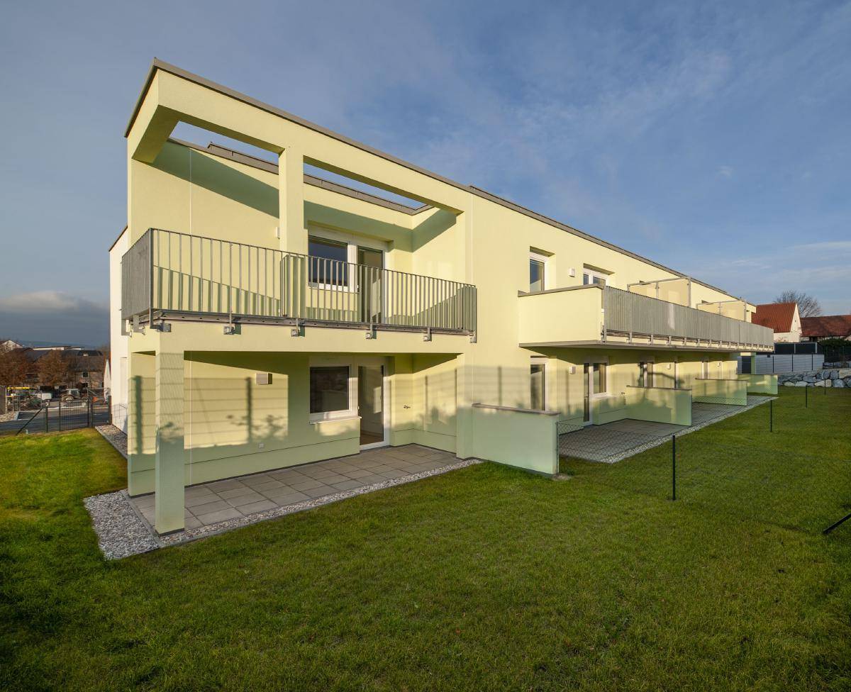 Moderne Architektur des Gebäudes mit Balkonen, Terrassen und gepflegter Rasenfläche.
