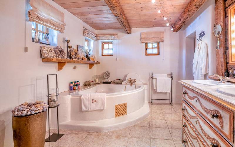 Geräumiges Badezimmer mit Eckbadewanne, Doppelwaschbecken und Fliesenboden.
