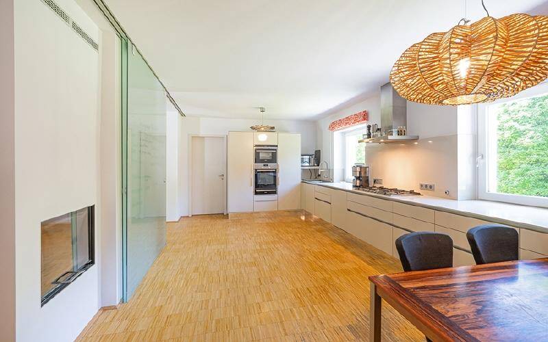 Moderne Küche mit hellen Fronten, Holzboden und integrierten Geräten, offen zum Essbereich.