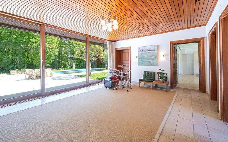 Heller Raum mit Holzdecke, großen Glasfronten und direktem Zugang zum Außenbereich mit Pool.