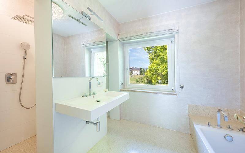 Modernes Badezimmer mit bodengleicher Dusche, großem Waschbecken und Fenster mit Ausblick.