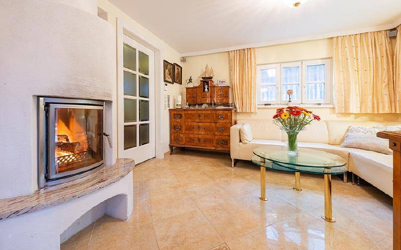 Gemütliches Wohnzimmer mit Kamin, hellen Fliesenböden und bequemer Sitzecke für entspannte Stunden.