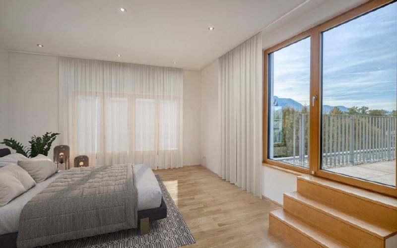 Helles Schlafzimmer mit Holzboden und großen Fenstern, die viel Tageslicht hereinlassen.