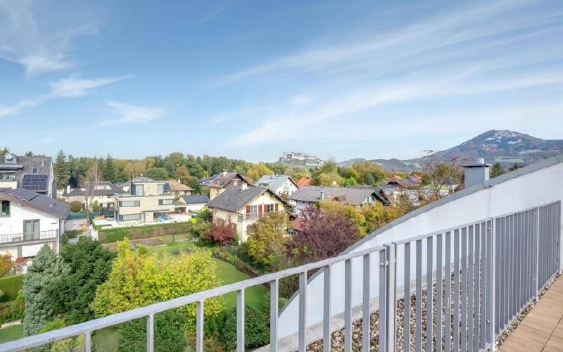 Weitläufiger Blick über die grüne Umgebung und die umliegenden Häuser von der Terrasse.