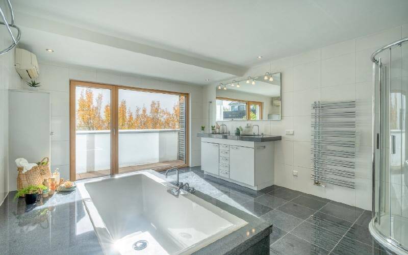 Großes, modernes Badezimmer mit Badewanne, Doppelwaschbecken und Zugang zum Balkon.