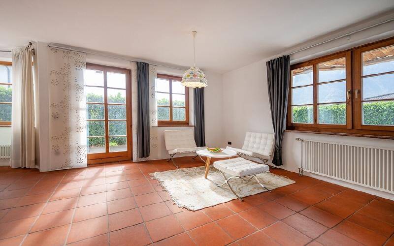 Helles Wohnzimmer mit Terrakottaboden, großen Fenstern und direktem Zugang zum Garten.