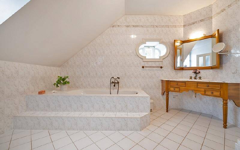 Geräumiges Badezimmer mit Badewanne, Fliesenboden und Dachschräge.