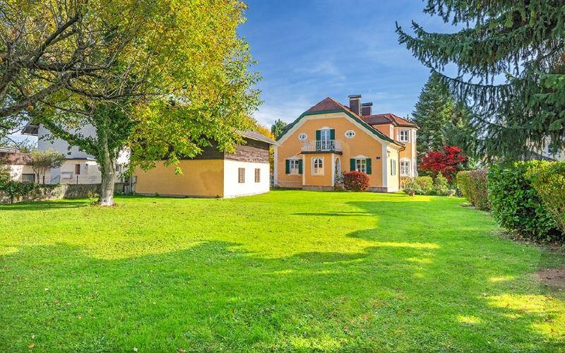 Weitläufiger grüner Garten mit altem Baumbestand und dem charmanten Wohnhaus im Hintergrund.