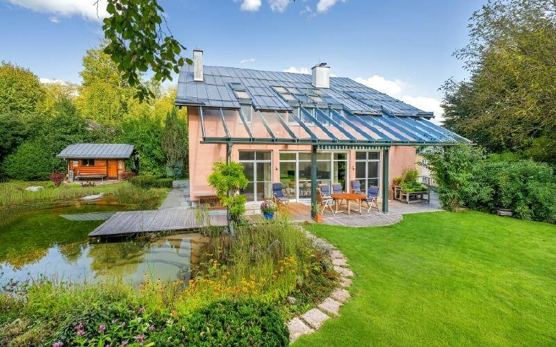 Ansicht des Hauses mit großem Garten, Teich und sonniger Terrasse.