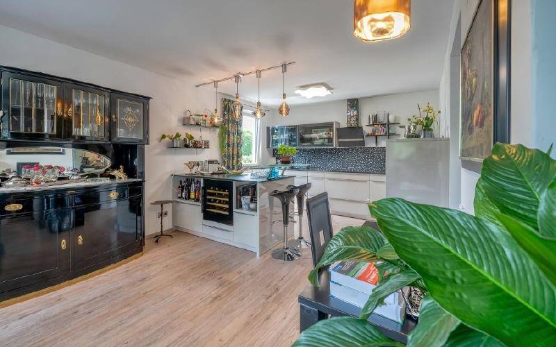Offener Wohn- und Essbereich mit moderner Küche, Holzboden und stilvollem Sideboard.
