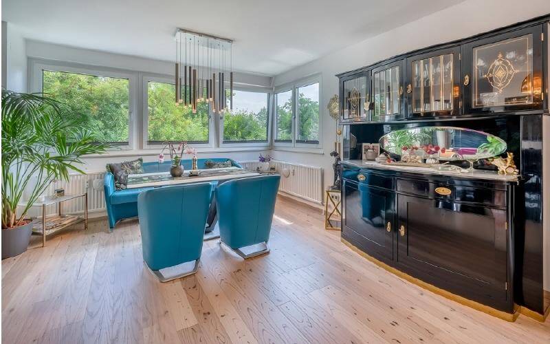 Eleganter Essbereich mit Holzboden, großem Fenster und einem antiken Sideboard.