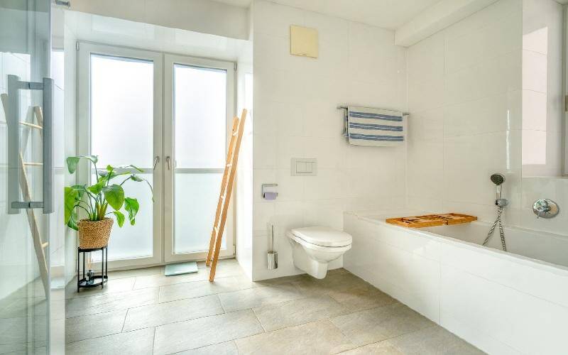 Helles Badezimmer mit Badewanne, WC und großem Fenster für viel Tageslicht.