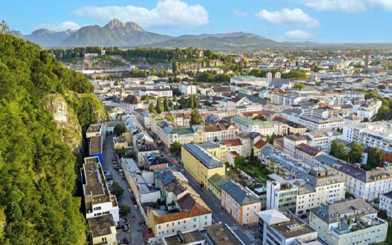Panoramablick über eine Stadt mit historischen Gebäuden und majestätischen Bergen im Hintergrund.