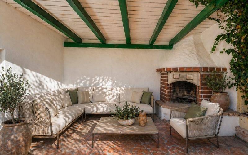 Gemütliche überdachte Terrasse mit Außenkamin, bequemen Loungemöbeln und Holzbalkendecke.