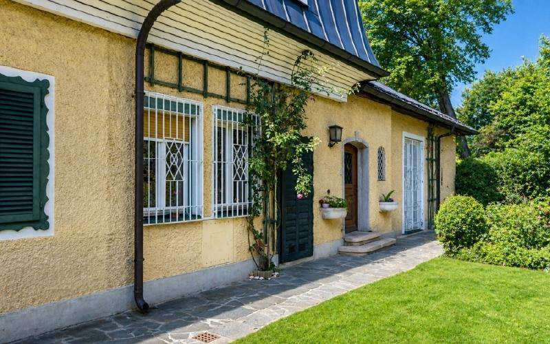 Detailansicht der gelben Fassade mit grünen Fensterläden und schmiedeeisernen Gittern.