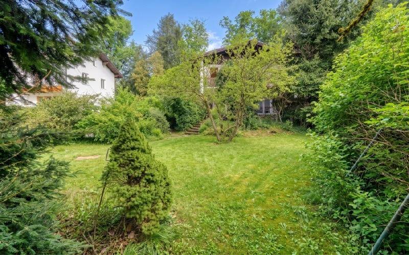 Idyllischer Gartenbereich mit viel Grün, Bäumen und einem gepflegten Rasen.