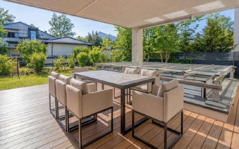 Überdachte Holzterrasse mit bequemen Gartenmöbeln und Blick ins Grüne.