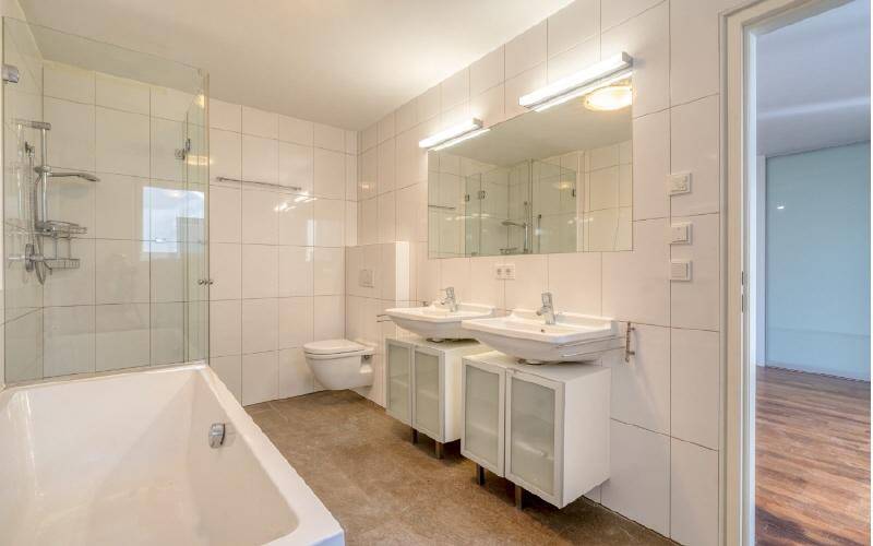 Modernes Badezimmer mit weißen Fliesen, Doppelwaschbecken, Badewanne und begehbarer Dusche.