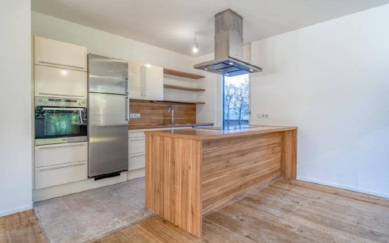 Moderne Küche mit Kücheninsel aus Holz, weißen Schränken und Edelstahlgeräten.