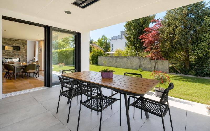 Überdachte Terrasse mit Esstisch und Stühlen, direkt am grünen Garten gelegen.