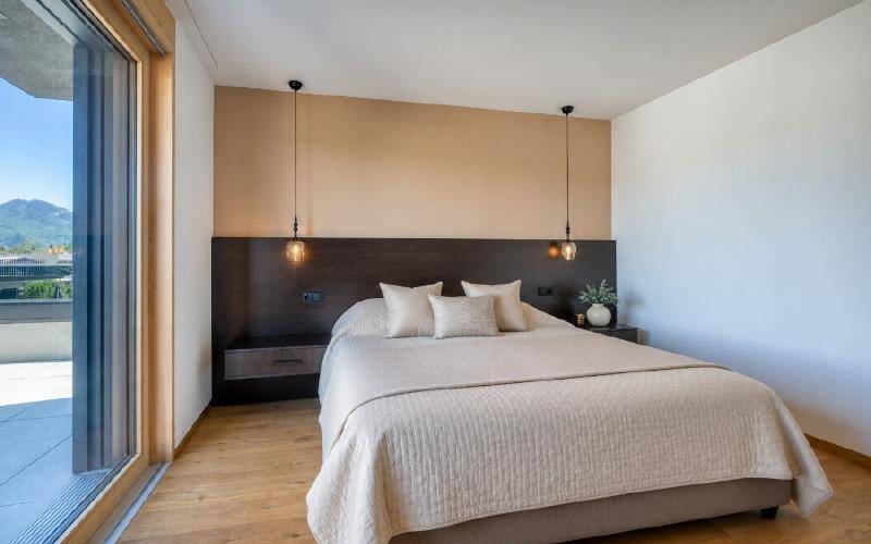 Helles Schlafzimmer mit Holzboden, minimalistischer Einrichtung und Zugang zur Terrasse.