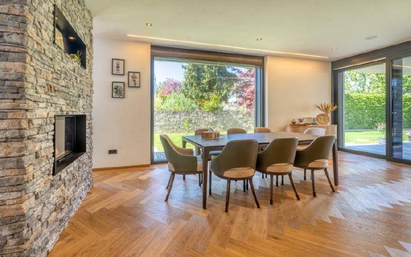 Heller Essbereich mit Holzboden, Steinfassade und großem Fenster zum Garten.