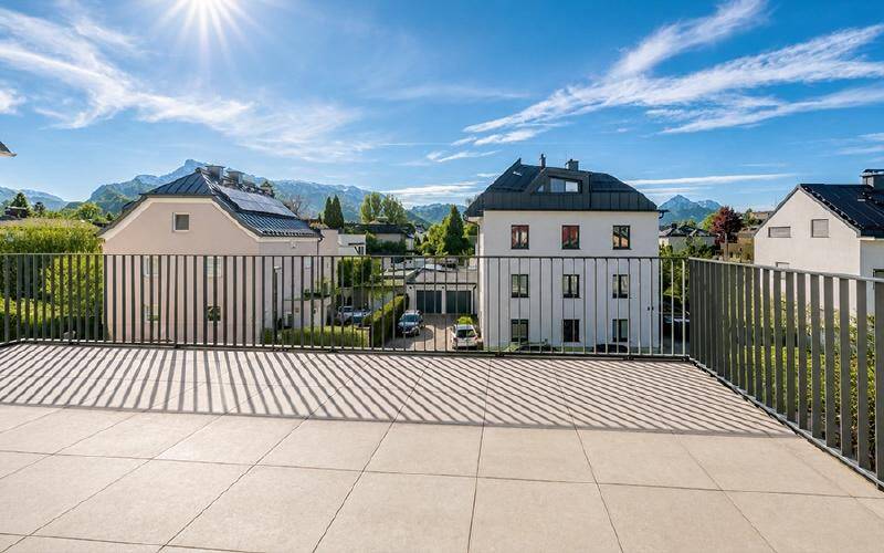 Sonniger Terrassenbereich mit Fliesenboden und weitem Blick auf die Berge und die Umgebung.