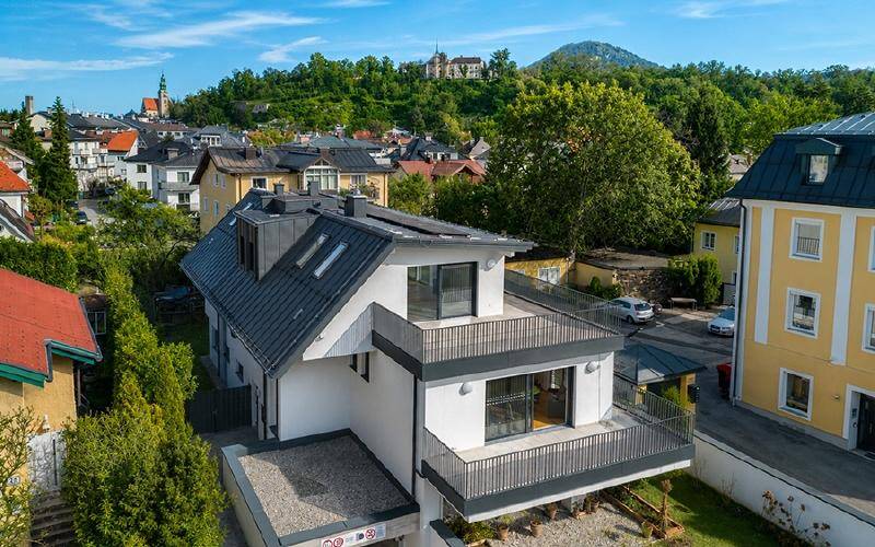 Modernes Wohngebäude mit mehreren Balkonen und Terrassen in einer grünen Stadtrandlage.