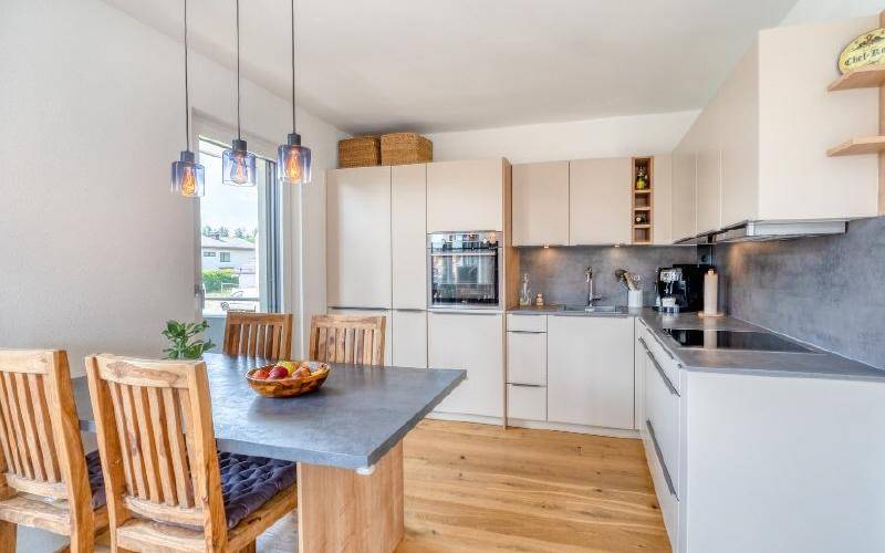 Moderne Einbauküche mit hellem Design, Essbereich und hochwertigen Geräten.