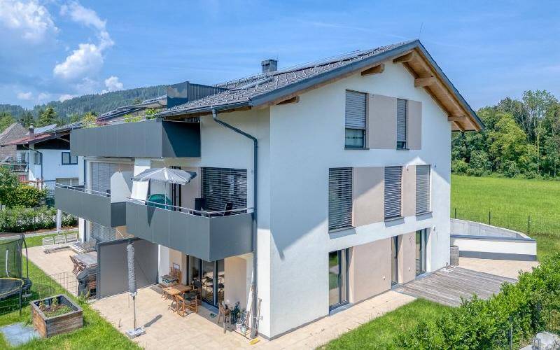 Modernes Wohnhaus mit Balkonen, Terrasse und gepflegtem Gartenbereich.