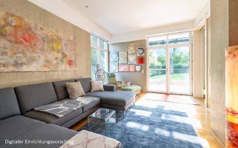 Gemütliches Wohnzimmer mit großem Ecksofa, farbenfroher Kunst und Zugang zum grünen Außenbereich.