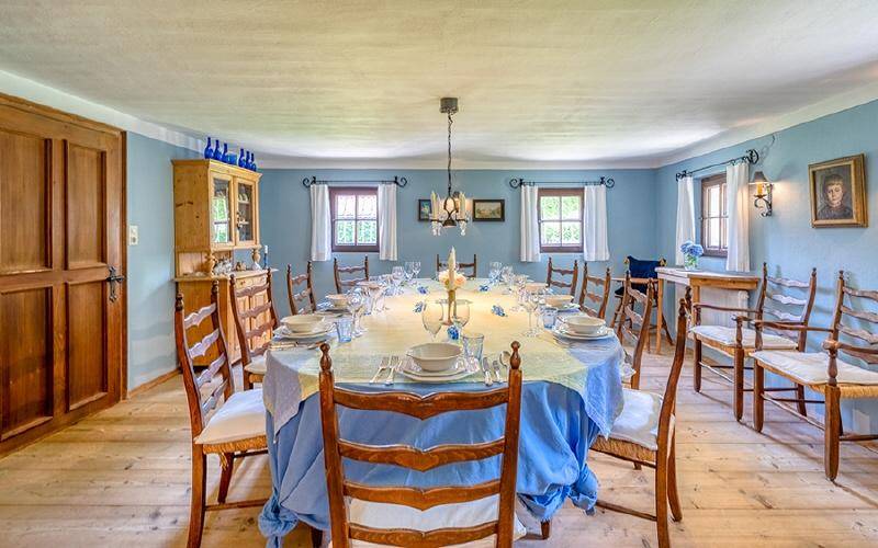 Geräumiges Esszimmer mit großem Holztisch, blauen Wänden und traditionellen Holzmöbeln.