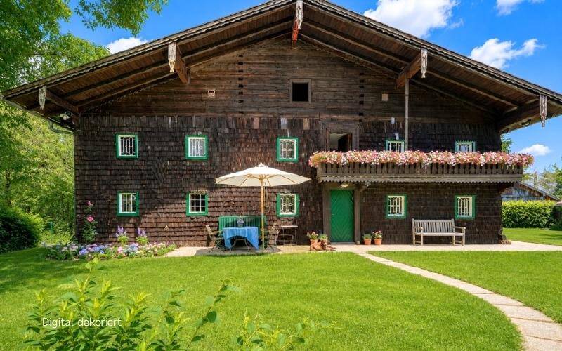 Traditionelle Holzfassade eines Hauses mit grünen Fensterläden und einem kleinen Sitzbereich im Garten.