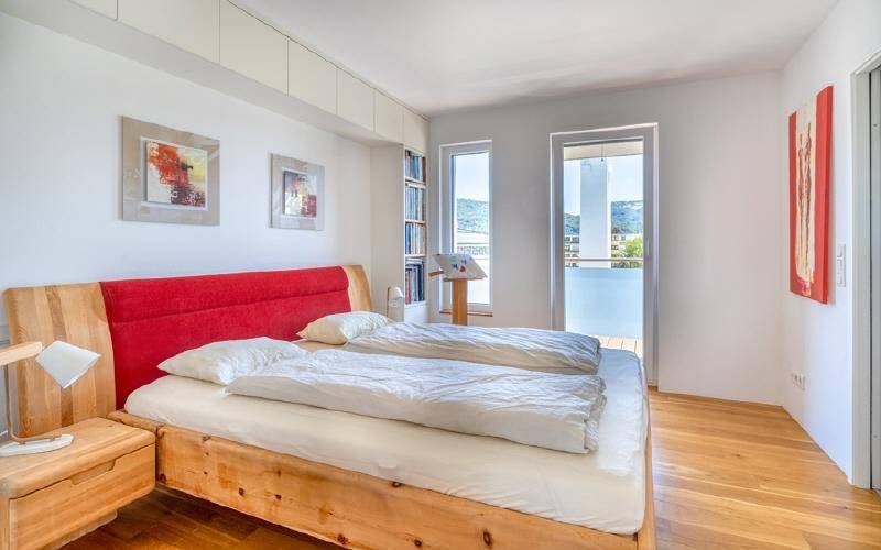 Helles Schlafzimmer mit Holzbett, Einbauschränken und Zugang zur Terrasse mit Bergblick.
