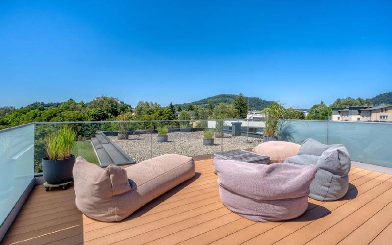 Sonnige Dachterrasse mit bequemen Sitzsäcken und weitem Blick über die grüne Landschaft.