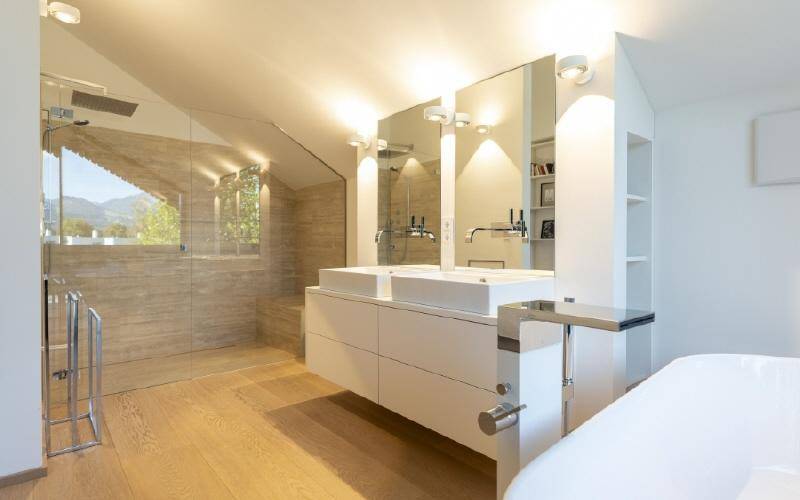 Modernes Badezimmer mit Doppelwaschbecken, großer begehbarer Dusche und Holzboden.