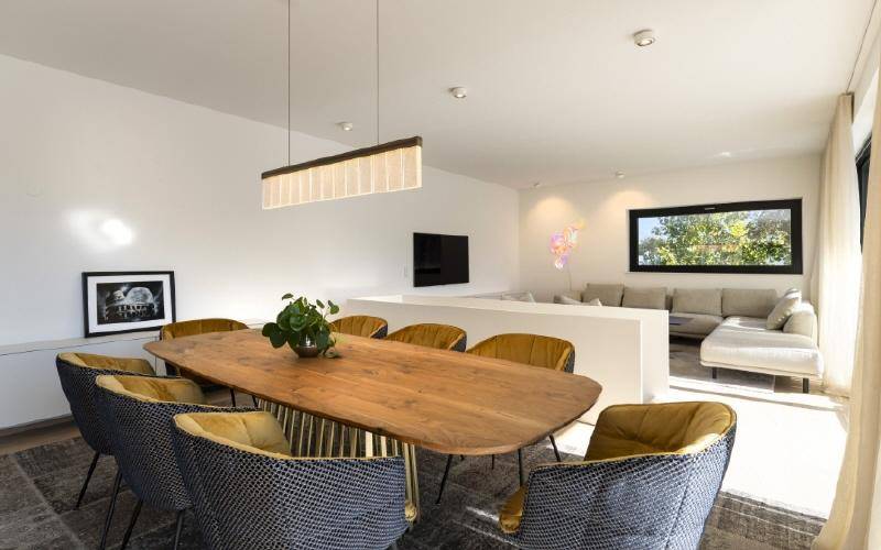 Eleganter Essbereich mit großem Holztisch, modernen Stühlen und offener Verbindung zum Wohnzimmer.