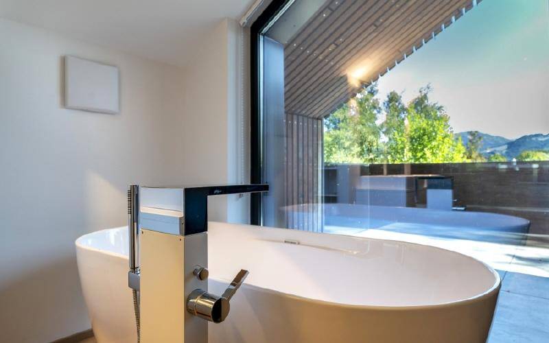 Elegante freistehende Badewanne mit Blick auf die umliegende Landschaft und Berge.