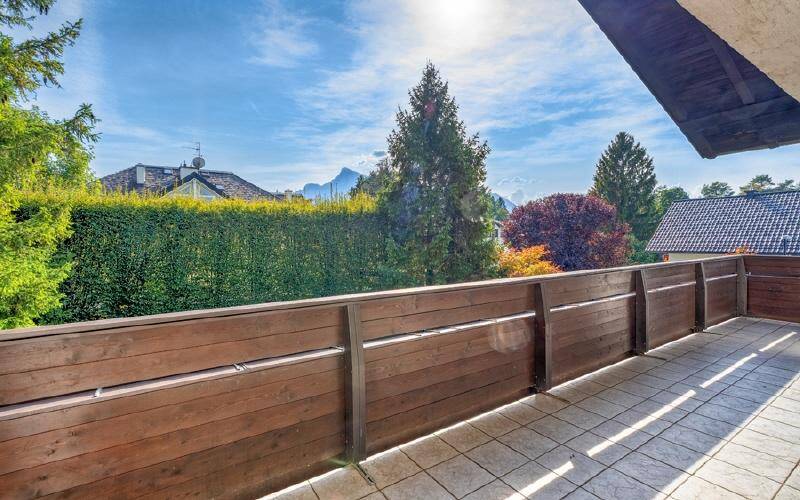 Geräumiger Balkon mit Holzbalkonbrüstung und weitem Blick auf die Berge und grüne Umgebung.
