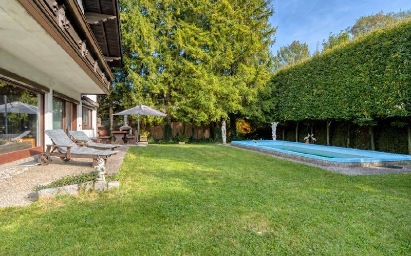 Großer Garten mit Rasenfläche, Swimmingpool und hohen Hecken für Privatsphäre.