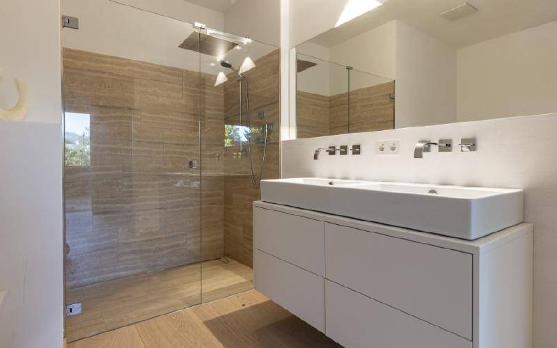 Modernes Badezimmer mit Doppelwaschbecken, großer Spiegelfläche und begehbarer Regendusche.