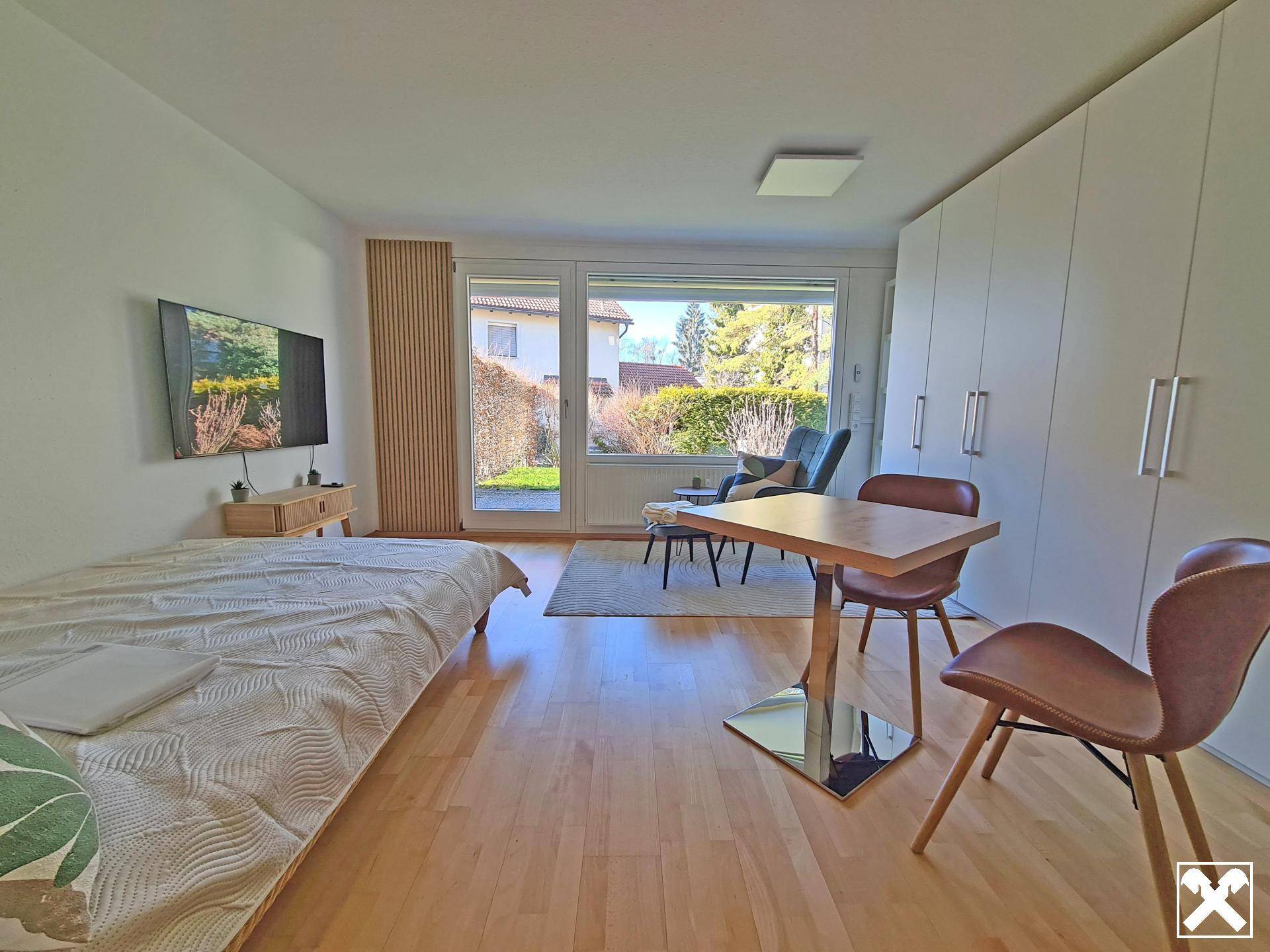 Helles Schlafzimmer mit Holzboden, großem Fenster und direktem Zugang zum Garten.