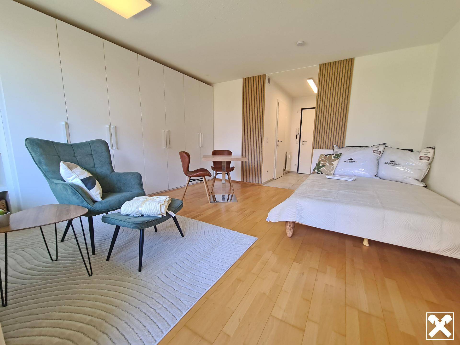 Modern eingerichtetes Schlafzimmer mit viel Stauraum und gemütlicher Sitzecke.