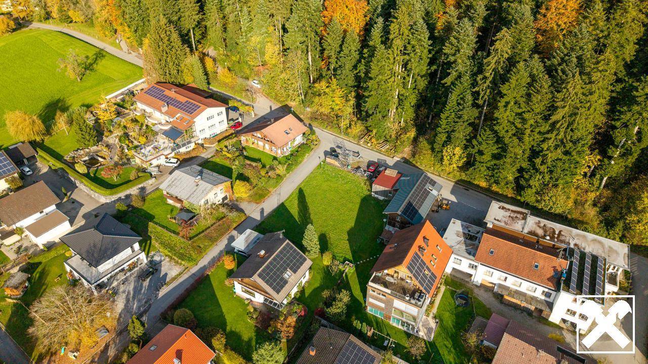 Luftaufnahme einer Wohnsiedlung mit Einfamilienhäusern und angrenzendem Waldgebiet.