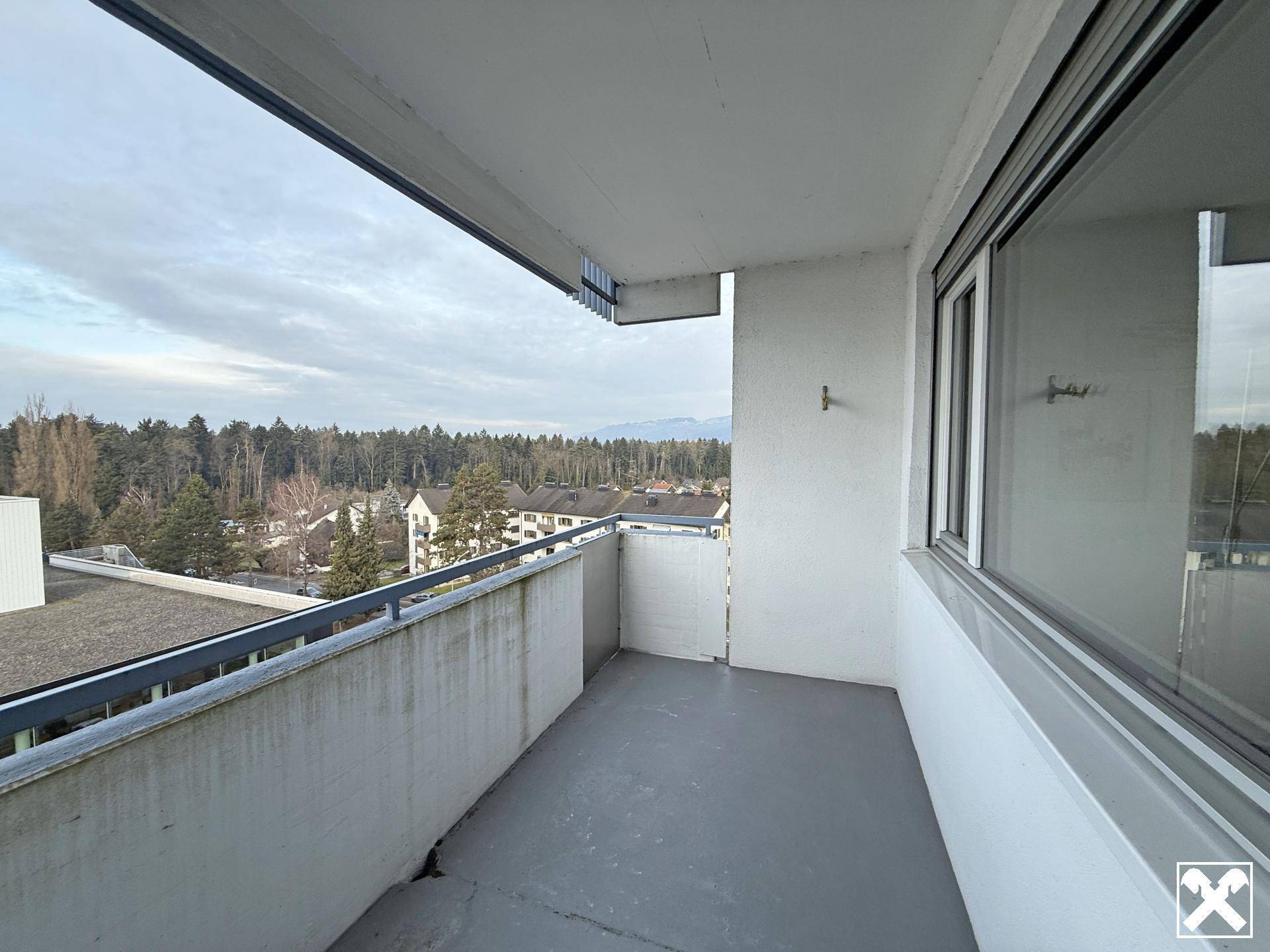 Balkon mit weitem Blick über eine grüne Landschaft und entfernte Berge.